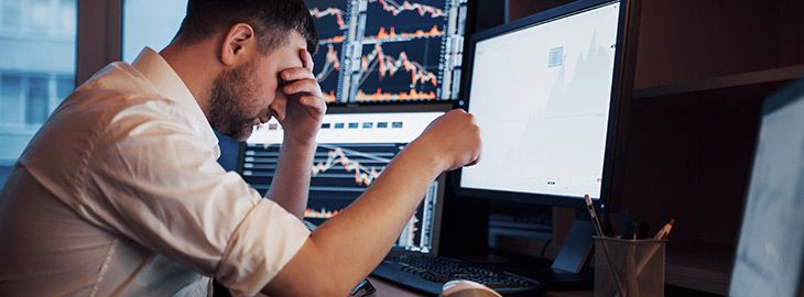 Young businessman holding hands on his face while sitting at his computer