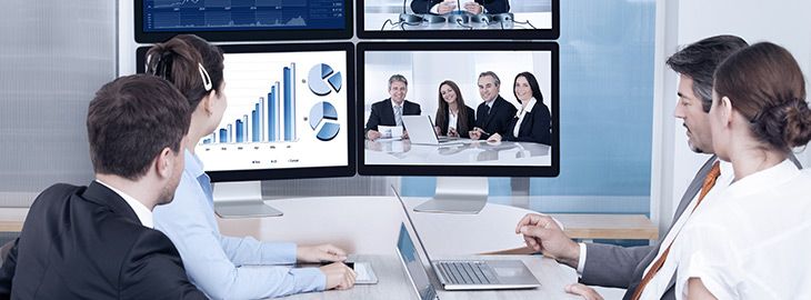 Businesspeople Sitting In A Conference Room Looking At Computer Screen teleconferencing with vendors