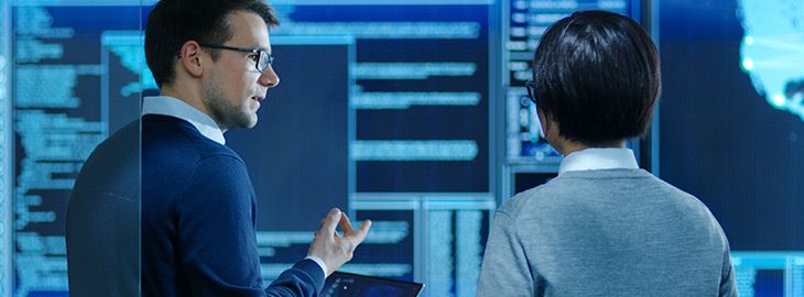 In the System Control Room IT Specialist and Project Engineer Have Discussion while Holding Laptop