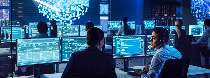 Confident Female Data Scientist Works Closely to her Young Colleague in Big Control and Monitoring Room