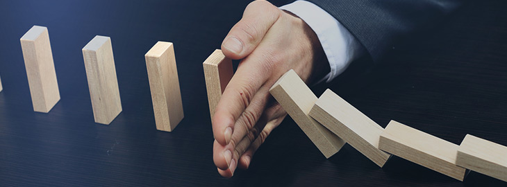 businessman stopping dominos from falling