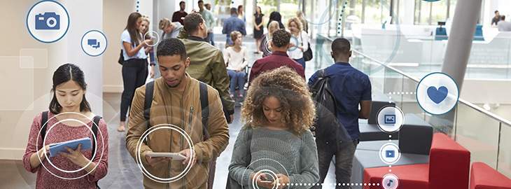 college students using mobile and tablet devices with social icons hovering around them