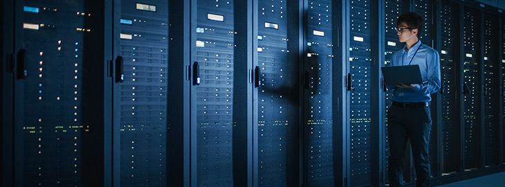 IT Specialist Walks along the Row of Operational Server Racks, Uses Laptop for Maintenance