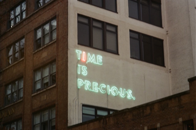 LED sign on side of building saying "Time is precious"