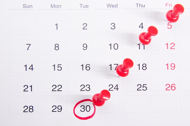 White calendar with black text and red pins, 30th circled in red marker